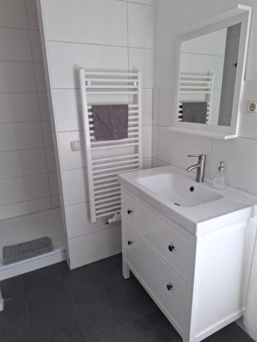 a white bathroom with a sink and a mirror at Villa 32 in Kröpelin