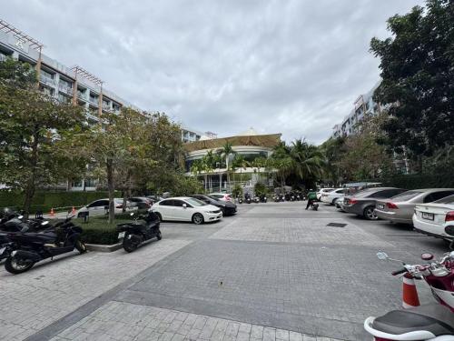 a parking lot with parked cars and motorcycles at Dusit Grand Park 1 in Jomtien Beach