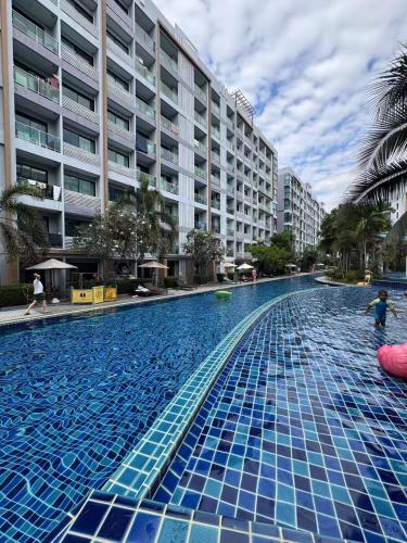 a large swimming pool with blue tiles in front of a building at Dusit Grand Park 1 in Jomtien Beach