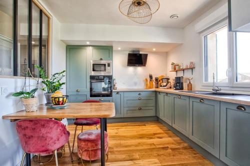 une cuisine avec une table en bois et des chaises roses dans l'établissement Maison entre Mer et détente !, à Colleville-Montgomery