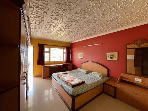 a bedroom with a bed and a red wall at Aarroh villa in Coonoor