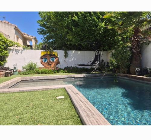 une piscine avec une peinture d'un visage sur un mur dans l'établissement Grande maison près du centre, à La Celle-sous-Gouzon