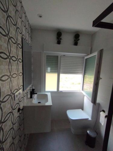 a bathroom with a white toilet and a sink at Chalet Lanzada in Sanxenxo