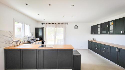 une cuisine avec des armoires noires et un comptoir en bois dans l'établissement Le Refuge des Jours Tranquilles, à Pont-Évêque