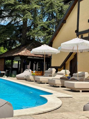 a pool with chairs and umbrellas next to a building at Vila Aleksić in Smederevo