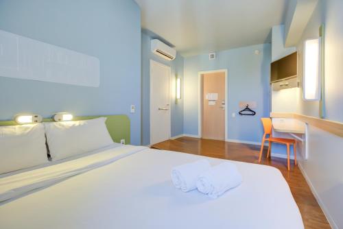 a bedroom with a large white bed with two towels at ibis budget Rio de Janeiro Nova America in Rio de Janeiro