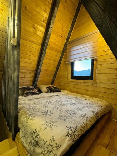 a bed in a log cabin with a window at Tara lux in Mojkovac