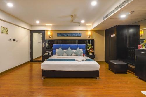 a bedroom with a large bed with a blue headboard at Quality Inn Bez Krishnaa in Visakhapatnam