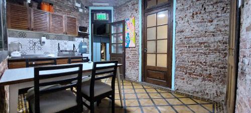 a kitchen with a counter with chairs and a brick wall at El Gran Gomero Hostal & Motoposada in Resistencia