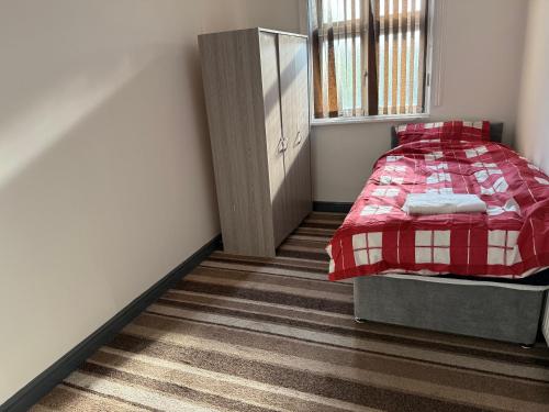 a bedroom with a bed with a red comforter and a window at Lux spacious 3BR entire apartment in Wakefield