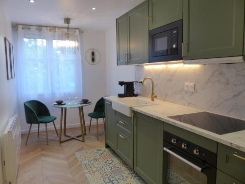 - une cuisine avec des placards verts, un évier et une table dans l'établissement Synécure Appartement, à Clamart