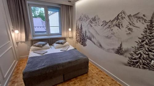 a bedroom with a bed with a mountain mural on the wall at Apartamenty Centrum dwupoziomowy 120 metrów in Nowy Targ