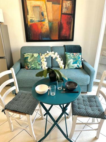 un salon avec un canapé bleu avec une table et des chaises dans l'établissement Magnifique 2 pièces à côté de la mer, à Nice