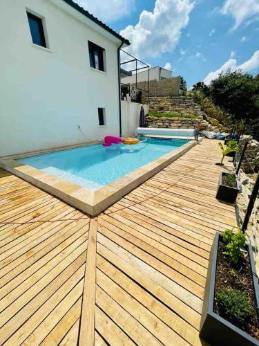 une terrasse en bois avec une piscine au-dessus d'une maison dans l'établissement House with pool between Nîmes and Montpellier, à Vauvert