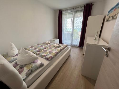 a bedroom with a bed and a window at Lillawellness Apartman 2 Siófok in Siófok