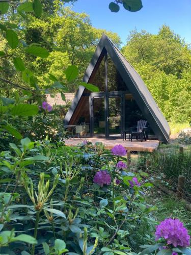 a cabin in the middle of a garden with flowers at A-huis in het bos van Drenthe in Norg