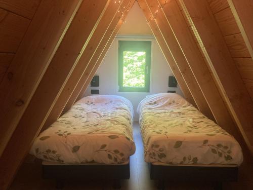 two beds in a small room with a window at A-huis in het bos van Drenthe in Norg