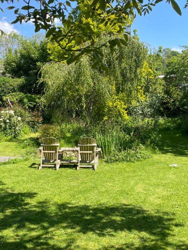 two benches sitting in the grass in a park at The Little House in Kilburn