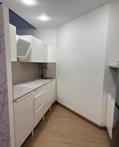 a white kitchen with white cabinets and a wooden floor at Cozy Studio Apartment in Dubai