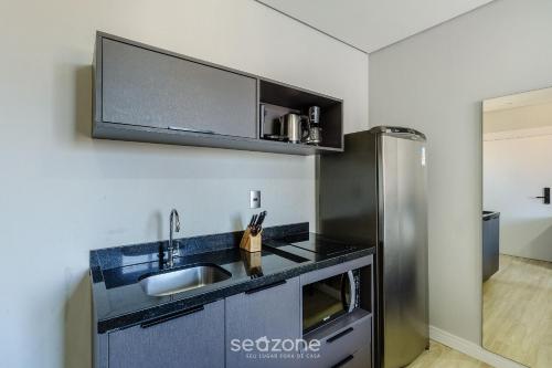 a kitchen with a sink and a stainless steel refrigerator at TCO - Apartamentos no Centro Histórico Porto Alegre/RS in Porto Alegre