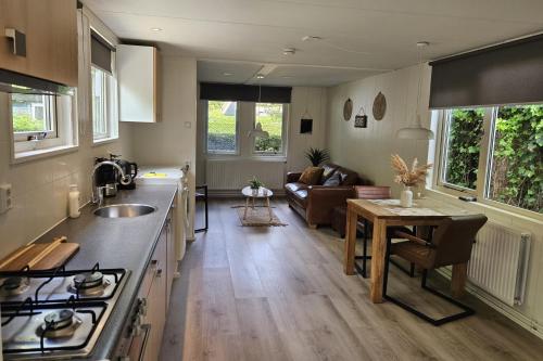 a kitchen and living room with a table and a couch at Zomerhuis Duinzicht in Egmond aan den Hoef