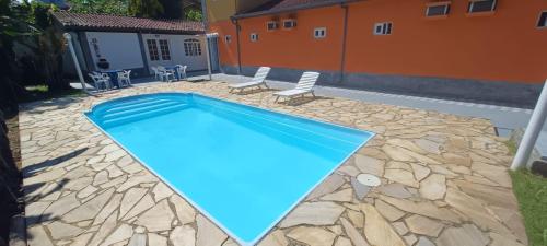 a swimming pool in a yard with two chairs and a house at Pousada Vila das Artes in Paraty