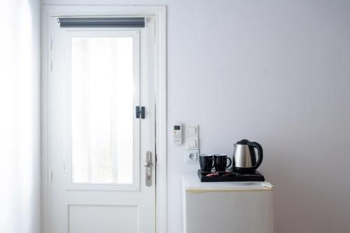 a white door with a coffee maker on top of a refrigerator at Pension Romantika in Matala