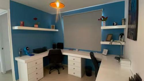 an office with a desk with two chairs and a blue wall at VALQUIRICO y VW A POCOS MINUTOS in Santa María Coronanco
