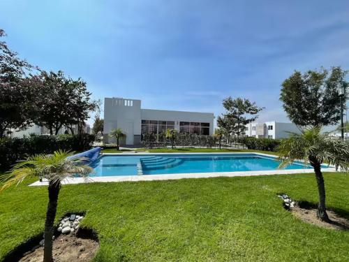 a swimming pool with palm trees in front of a building at VALQUIRICO y VW A POCOS MINUTOS in Santa María Coronanco