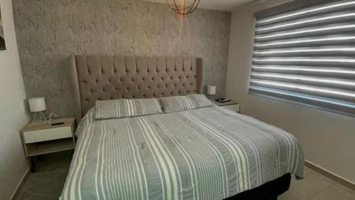 a bedroom with a bed with a striped comforter and a window at VALQUIRICO y VW A POCOS MINUTOS in Santa María Coronanco