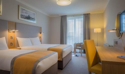 a hotel room with two beds and a desk at Maldron Hotel, Newlands Cross in Clondalkin 