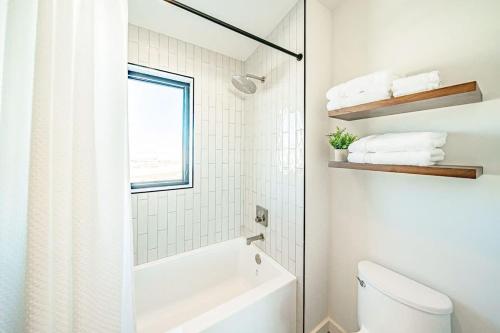 a white bathroom with a tub and a toilet at Luxury Retreat Epic Views & Hot Tub in Tetonia