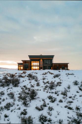 a house in a snowy field with the sun shining at Luxury Retreat Epic Views & Hot Tub in Tetonia