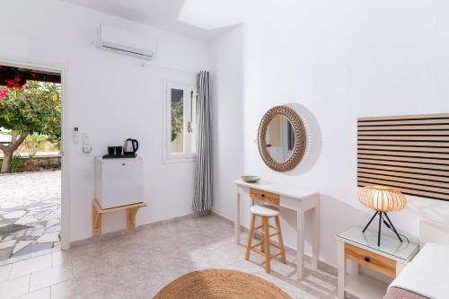 a white living room with a desk and a mirror at Pension Romantika in Matala