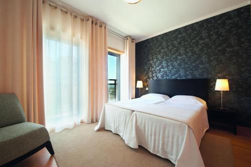 a bedroom with a large white bed and a window at Real Marina Residence in Olhão