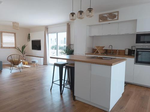 une cuisine avec des armoires blanches et un plancher en bois dans l'établissement Vilin Tréompan à 400 m de la plage, à Ploudalmézeau