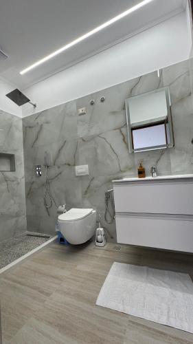 a bathroom with a sink and a toilet and a mirror at Amel's Apartments Comfortable Family Stay Near Orikum Beach in Orikum