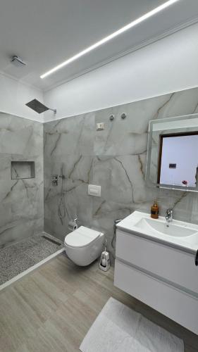 a bathroom with a white toilet and a sink at Amel's Apartments Comfortable Family Stay Near Orikum Beach in Orikum