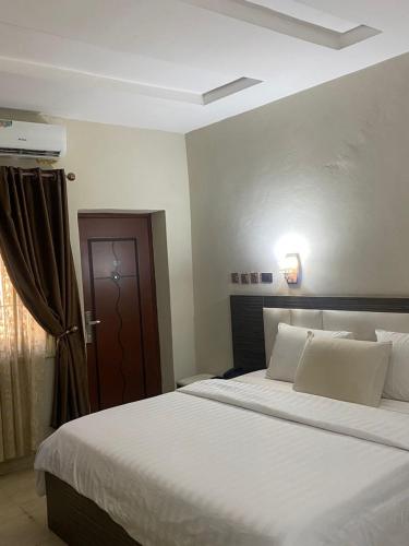 a bedroom with a large bed with white sheets at Tofana Hotel and Suites Mabushi in Abuja