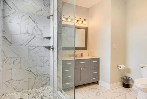 a bathroom with a glass shower with a toilet and a sink at San Souci By The Sea - Your Folly Beach Oasis in Folly Beach