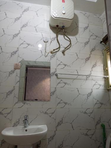 a bathroom with a sink and a light on the wall at Tofana Hotel and Suites Mabushi in Abuja