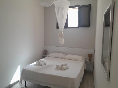a white bedroom with a bed with towels on it at Villetta Terranova 2 in Lampedusa