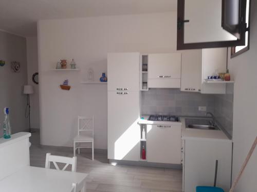 a kitchen with white cabinets and a table and chairs at Villetta Terranova 2 in Lampedusa
