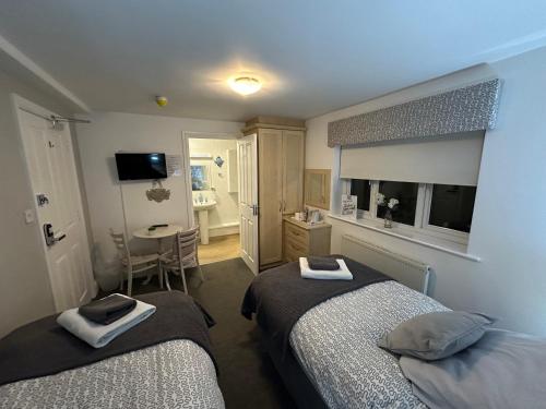 a bedroom with two beds and a table and a television at Station Approach B&B Boutique Stays in Solihull