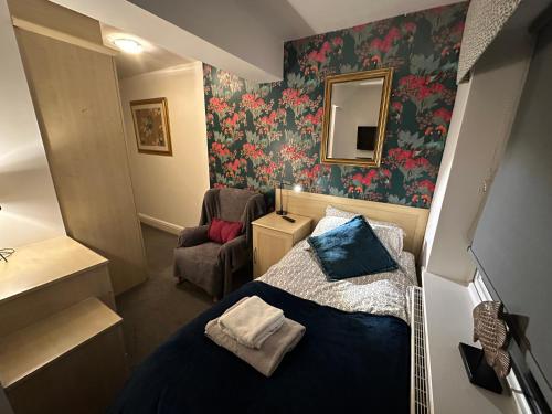 a small bedroom with a bed and a chair at Station Approach B&B Boutique Stays in Solihull
