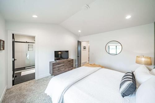 a white bedroom with a large bed and a television at Unique Townhome with AC Garage Patio in Driggs