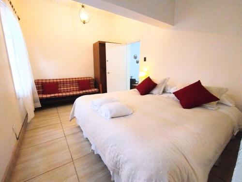 a bedroom with a large white bed with red pillows at Centro Mariápolis Chile in Cunaco