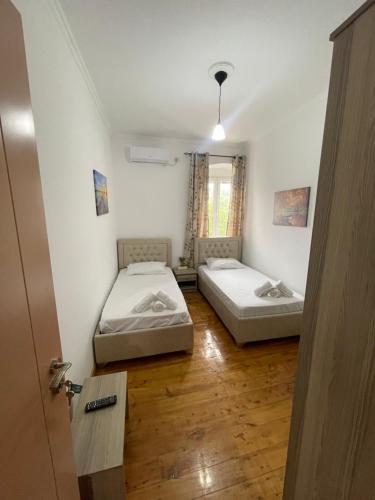two beds in a small room with a door at Little himara 1 in Himare