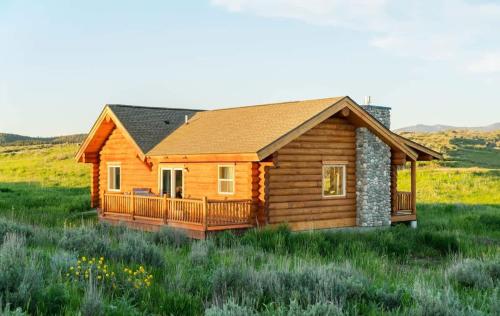 a log cabin with a deck in a field at Log Cabin Teton Views & Pets OK in Tetonia