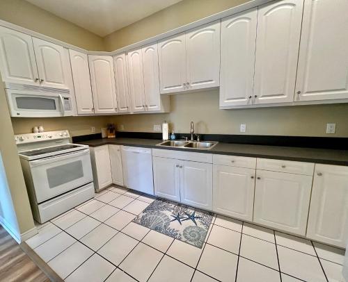 a white kitchen with white cabinets and a sink at Downtown, Roof Deck, Parking in Saugatuck